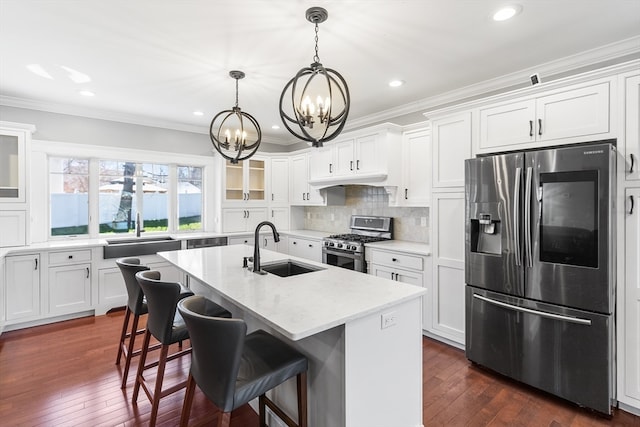 kitchen featuring sink, dark hardwood / wood-style flooring, stainless steel appliances, ornamental molding, and a kitchen island with sink