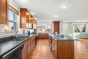 kitchen featuring sink, stainless steel stove, black dishwasher, light hardwood / wood-style flooring, and a kitchen island