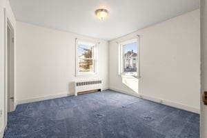 carpeted spare room with radiator heating unit