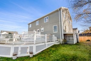 back of property featuring a lawn and a wooden deck