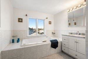 bathroom featuring vanity and tiled tub