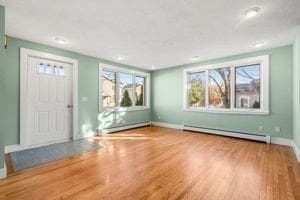 foyer entrance featuring hardwood / wood-style floors and a baseboard heating unit