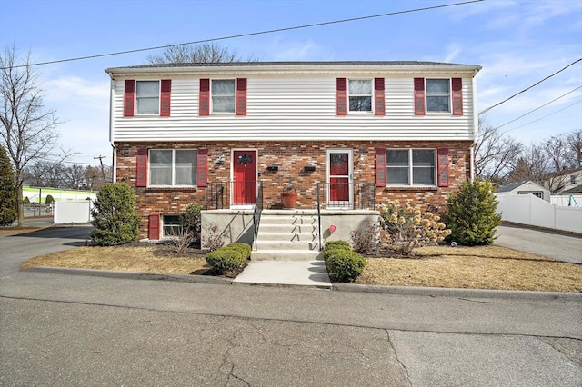 colonial-style house with fence and brick siding