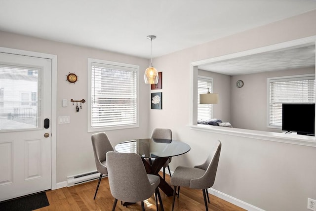 dining room with a baseboard radiator, baseboards, a healthy amount of sunlight, and wood finished floors