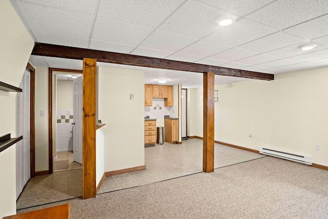 finished below grade area featuring a baseboard radiator, a paneled ceiling, and baseboards