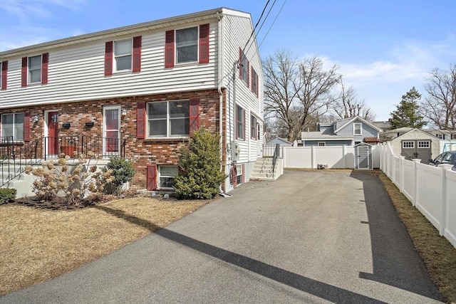 view of front of house featuring brick siding, an outdoor structure, and fence