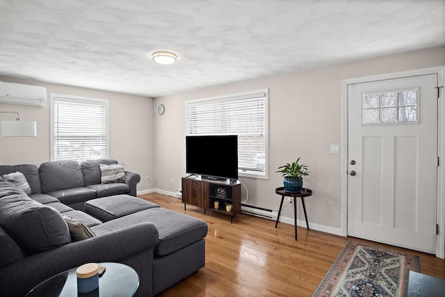 living area featuring a baseboard radiator, baseboards, light wood-style floors, and a wall unit AC