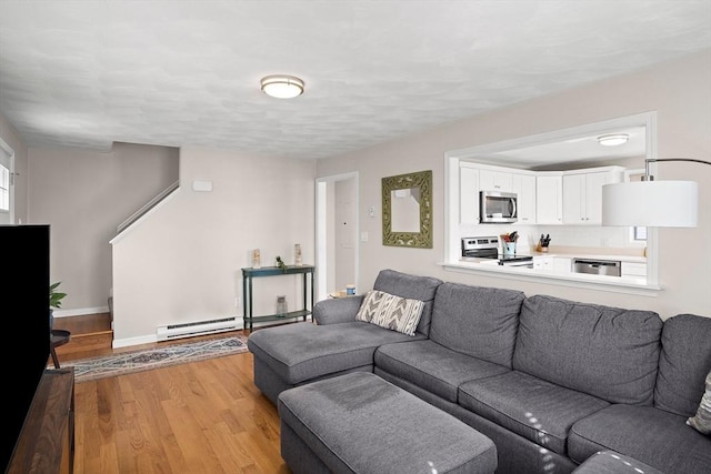 living area featuring a baseboard heating unit, baseboards, and light wood finished floors