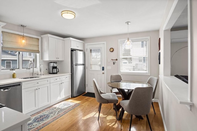 kitchen featuring a sink, decorative light fixtures, light wood-style floors, and stainless steel appliances