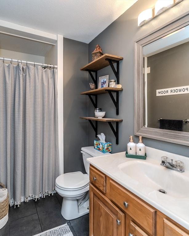 full bath featuring tile patterned flooring, toilet, vanity, and curtained shower
