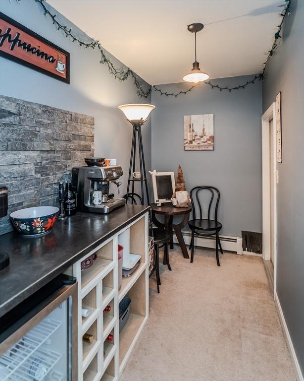 dining space with light colored carpet, beverage cooler, and a baseboard heating unit