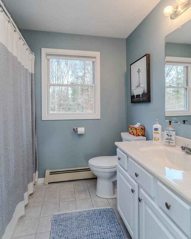 full bath with a baseboard radiator, tile patterned flooring, healthy amount of natural light, and toilet