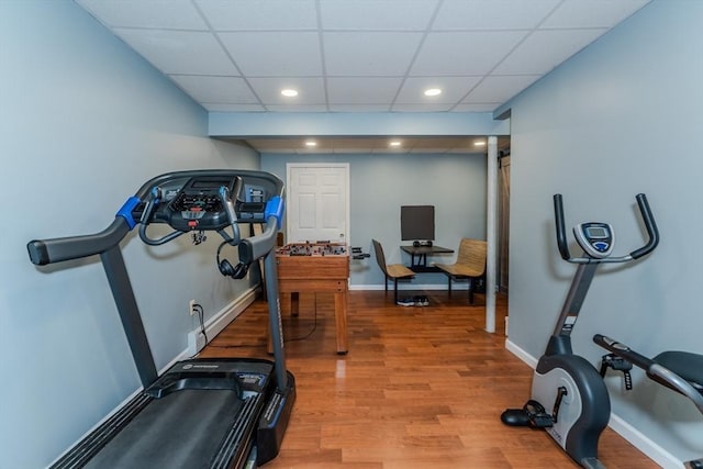 exercise area featuring a drop ceiling, wood finished floors, recessed lighting, and baseboards