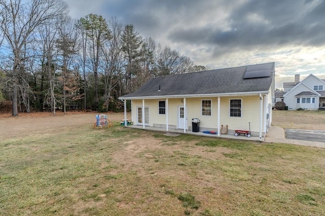 rear view of house with a patio area, solar panels, and a lawn