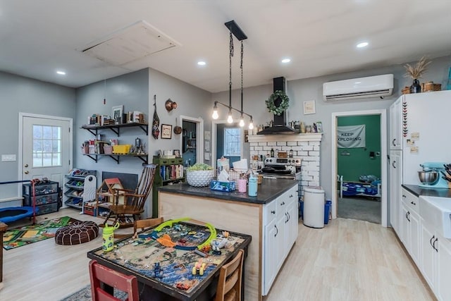 kitchen with a wall unit AC, dark countertops, light wood-style floors, white cabinets, and recessed lighting