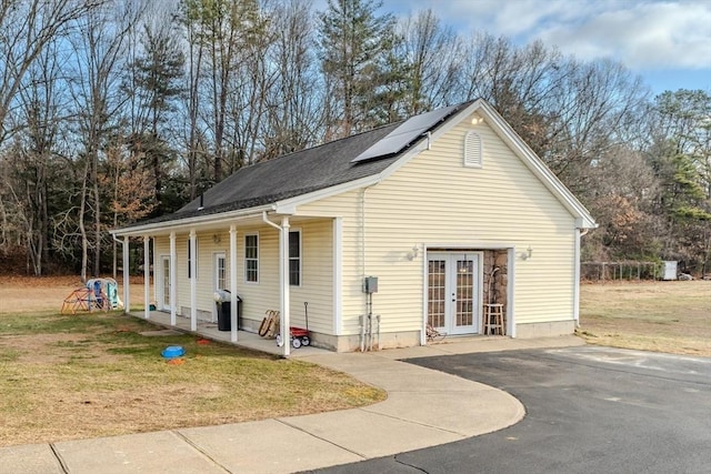 view of front of home with french doors, roof mounted solar panels, and a front yard