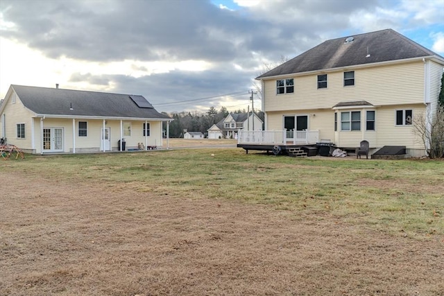 rear view of property with a yard, a wooden deck, and french doors