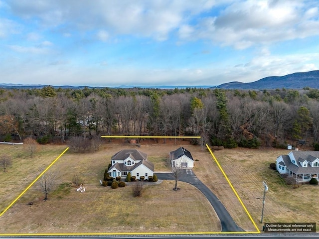view of subject property with a heavily wooded area and a mountain backdrop