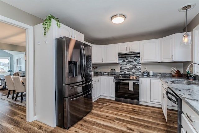 kitchen featuring appliances with stainless steel finishes, a sink, under cabinet range hood, light stone countertops, and white cabinetry