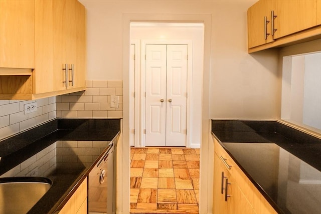 kitchen featuring decorative backsplash, dark stone countertops, dishwasher, and light brown cabinets