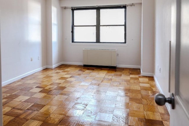 empty room featuring baseboards and radiator