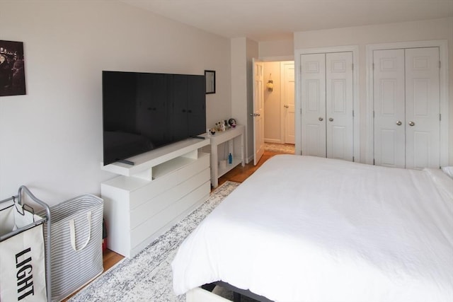 bedroom featuring two closets and wood finished floors