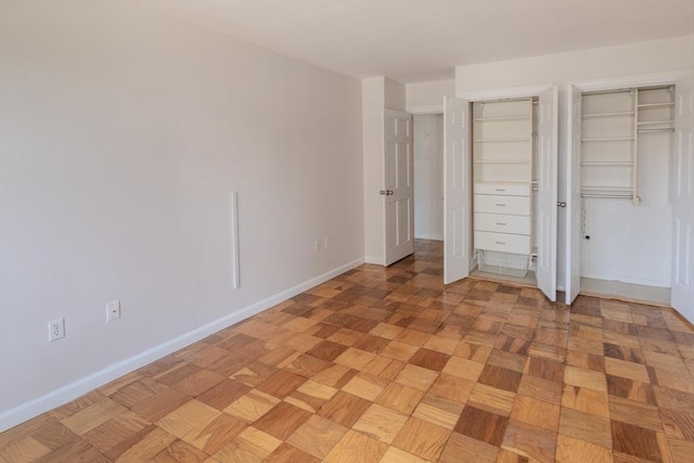 unfurnished bedroom with two closets and baseboards