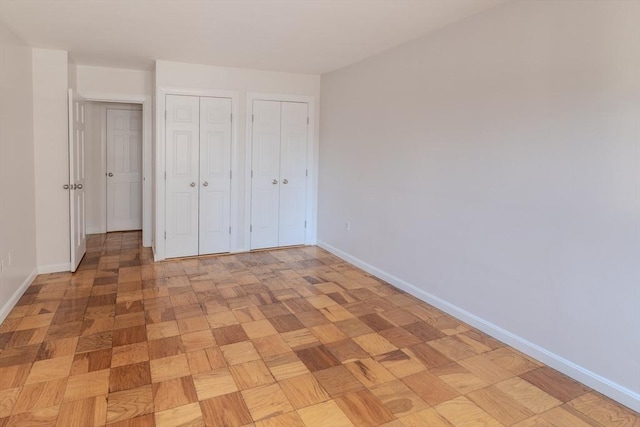 unfurnished bedroom featuring baseboards and multiple closets