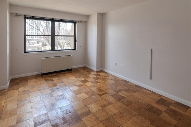 empty room with radiator heating unit and baseboards