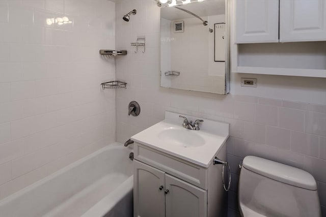 full bath featuring visible vents, tub / shower combination, toilet, vanity, and tile walls