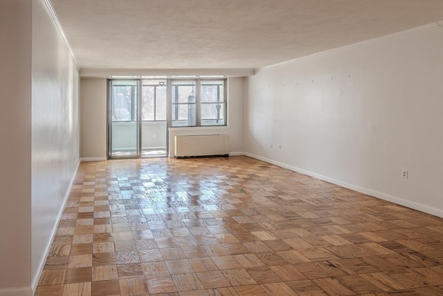 spare room featuring crown molding, radiator heating unit, and baseboards