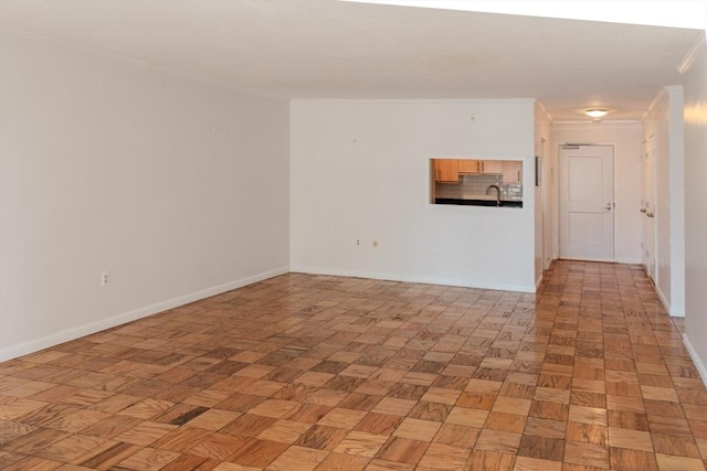 unfurnished room featuring a sink, baseboards, and ornamental molding