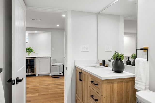 bathroom featuring wood-type flooring, wine cooler, vanity, and toilet