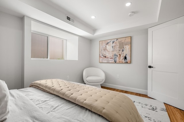 bedroom featuring a tray ceiling and hardwood / wood-style flooring