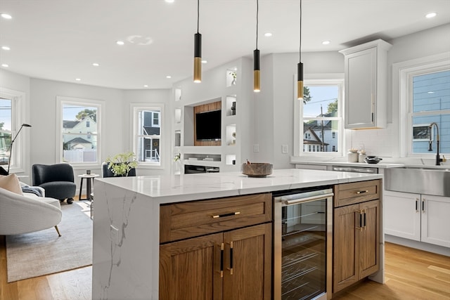 kitchen featuring light stone countertops, a healthy amount of sunlight, beverage cooler, and white cabinets