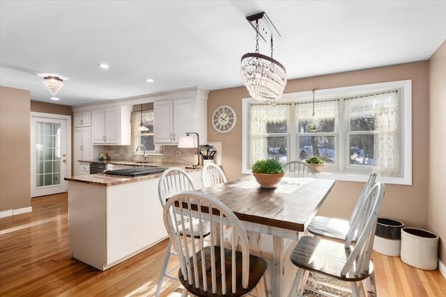 dining area with sink, a chandelier, and light wood-type flooring