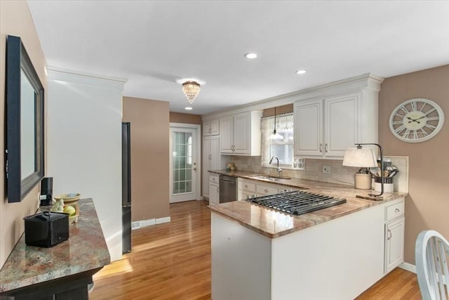 kitchen featuring sink, appliances with stainless steel finishes, white cabinetry, tasteful backsplash, and kitchen peninsula