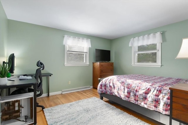 bedroom with light hardwood / wood-style floors and a baseboard heating unit