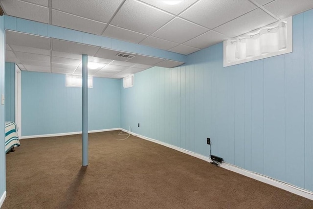 basement featuring dark carpet and a drop ceiling