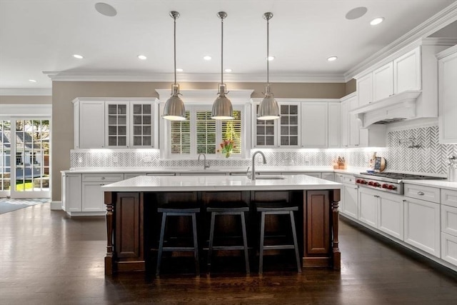 kitchen with stainless steel gas stovetop, pendant lighting, a center island with sink, and white cabinets