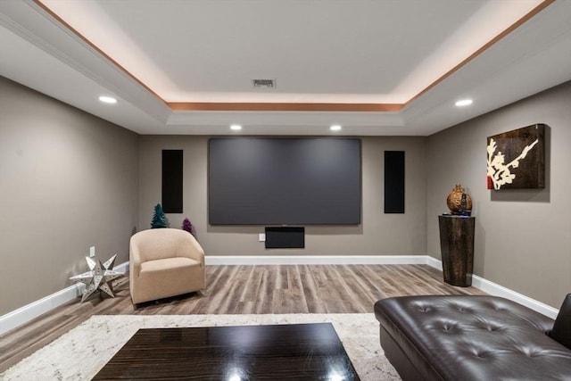 cinema room with light hardwood / wood-style flooring and a raised ceiling