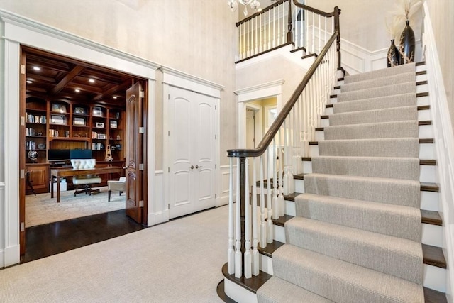 foyer entrance with a high ceiling, carpet, coffered ceiling, and beam ceiling