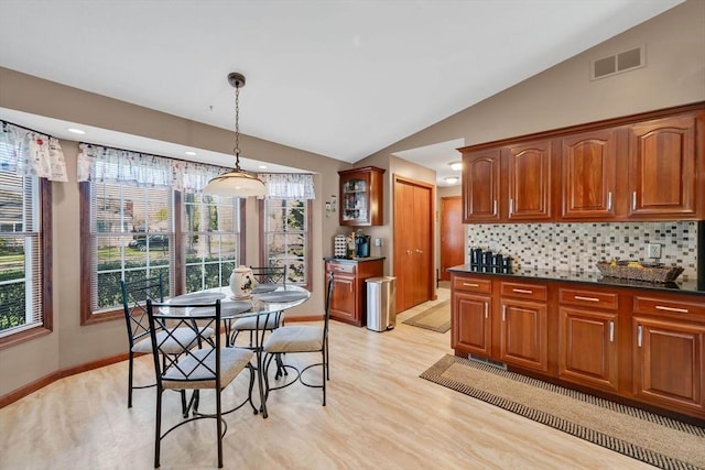 kitchen with visible vents, light wood finished floors, backsplash, and vaulted ceiling