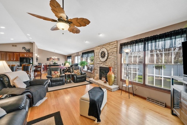 living area with ceiling fan, light wood-style floors, a fireplace, lofted ceiling, and visible vents