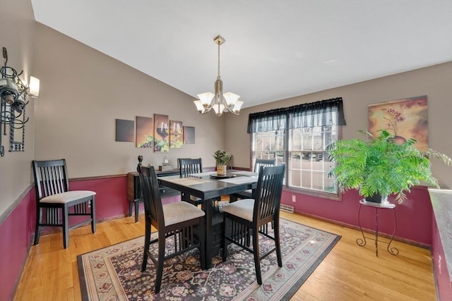 dining space featuring visible vents, a notable chandelier, wood finished floors, and lofted ceiling