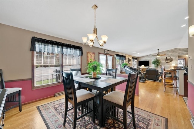 dining area featuring light wood finished floors, ceiling fan with notable chandelier, baseboards, vaulted ceiling, and visible vents