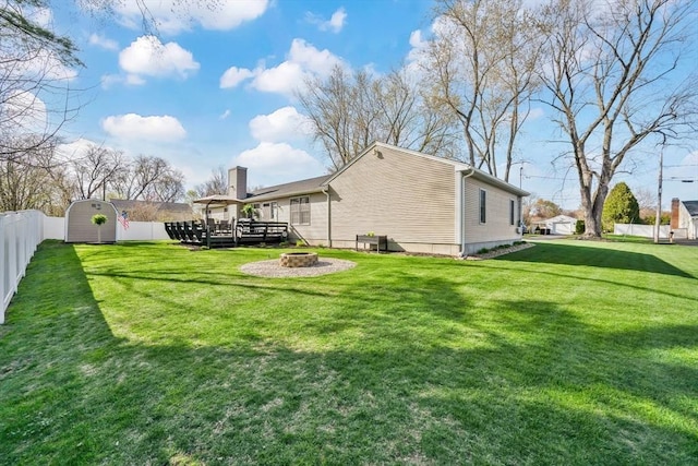 view of yard featuring an outdoor structure, a fenced backyard, a fire pit, and a storage shed