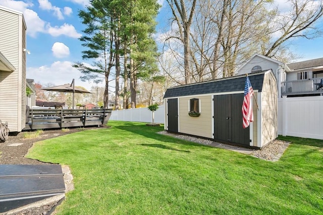 view of yard featuring a storage shed, a deck, an outbuilding, and a fenced backyard