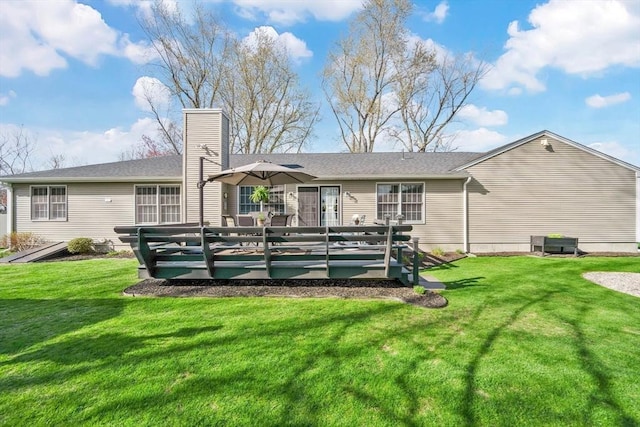 back of property featuring a chimney, a yard, and a deck