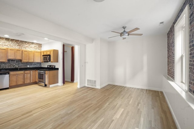 kitchen featuring baseboards, light wood finished floors, ceiling fan, tasteful backsplash, and appliances with stainless steel finishes